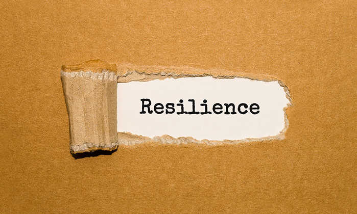 ripped paper reveals the word "resilience"
